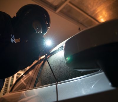 thief using a tool to break into a car.