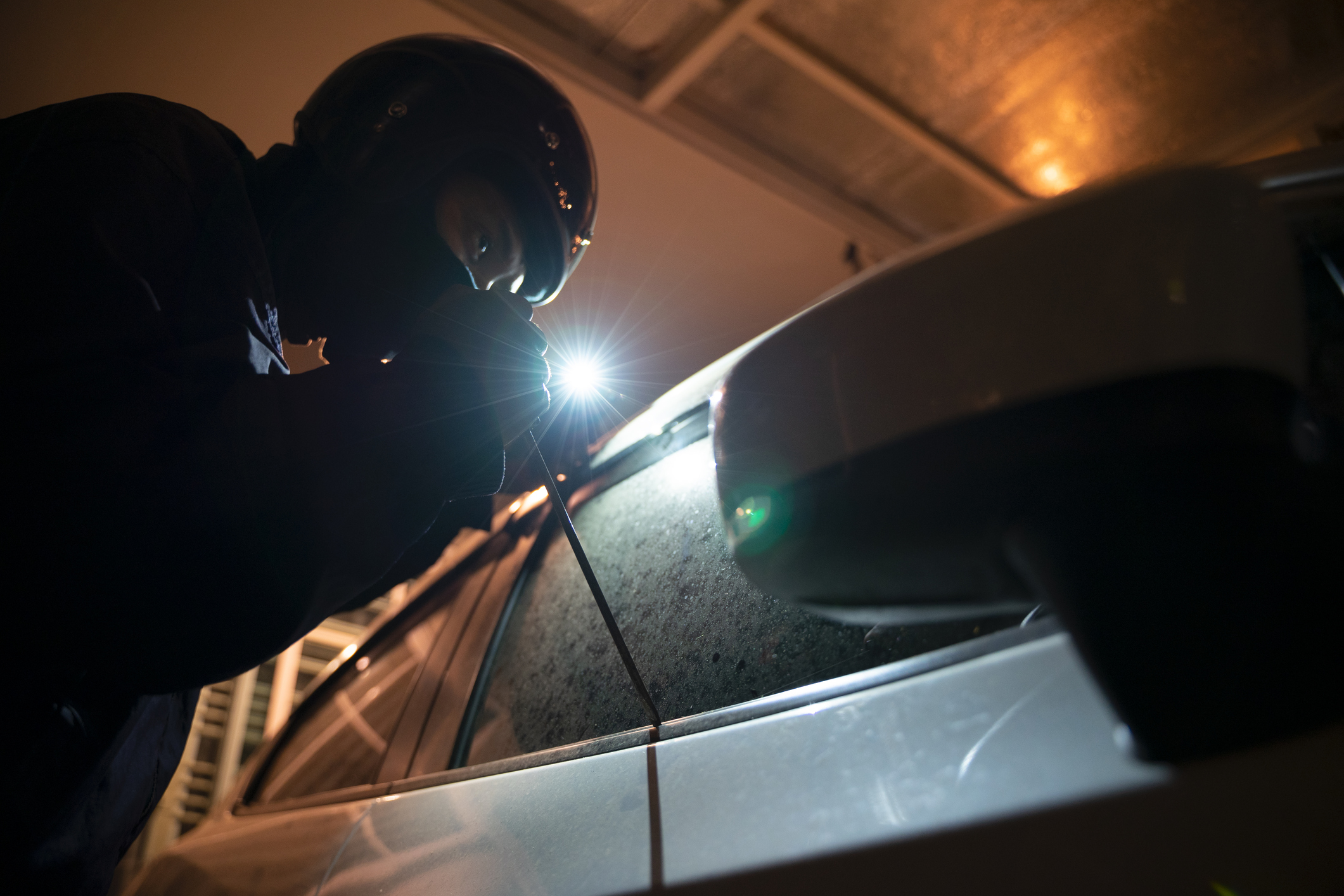 thief using a tool to break into a car.