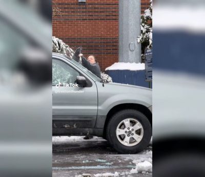 Mujer trata de quitar el hielo de su coche