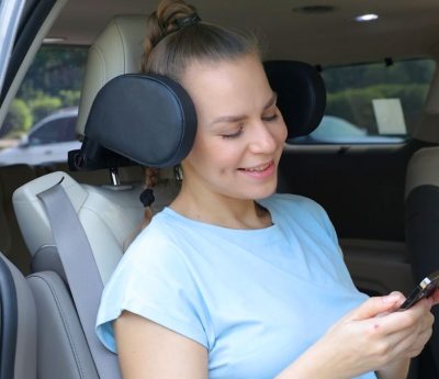Una mujer utilizando el reposacabezas ajustable del coche.