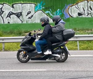 Pasajero de una moto utilizando el móvil